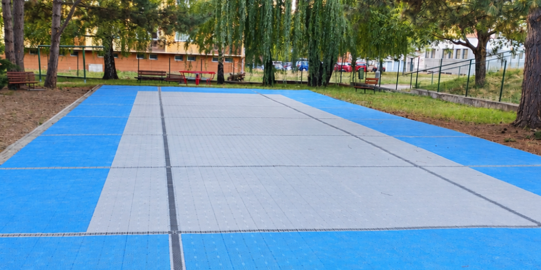 Rekonstruovaný povrch hřiště mateřské školy v Brně-Komíně s modrým okruhem a šedým středem